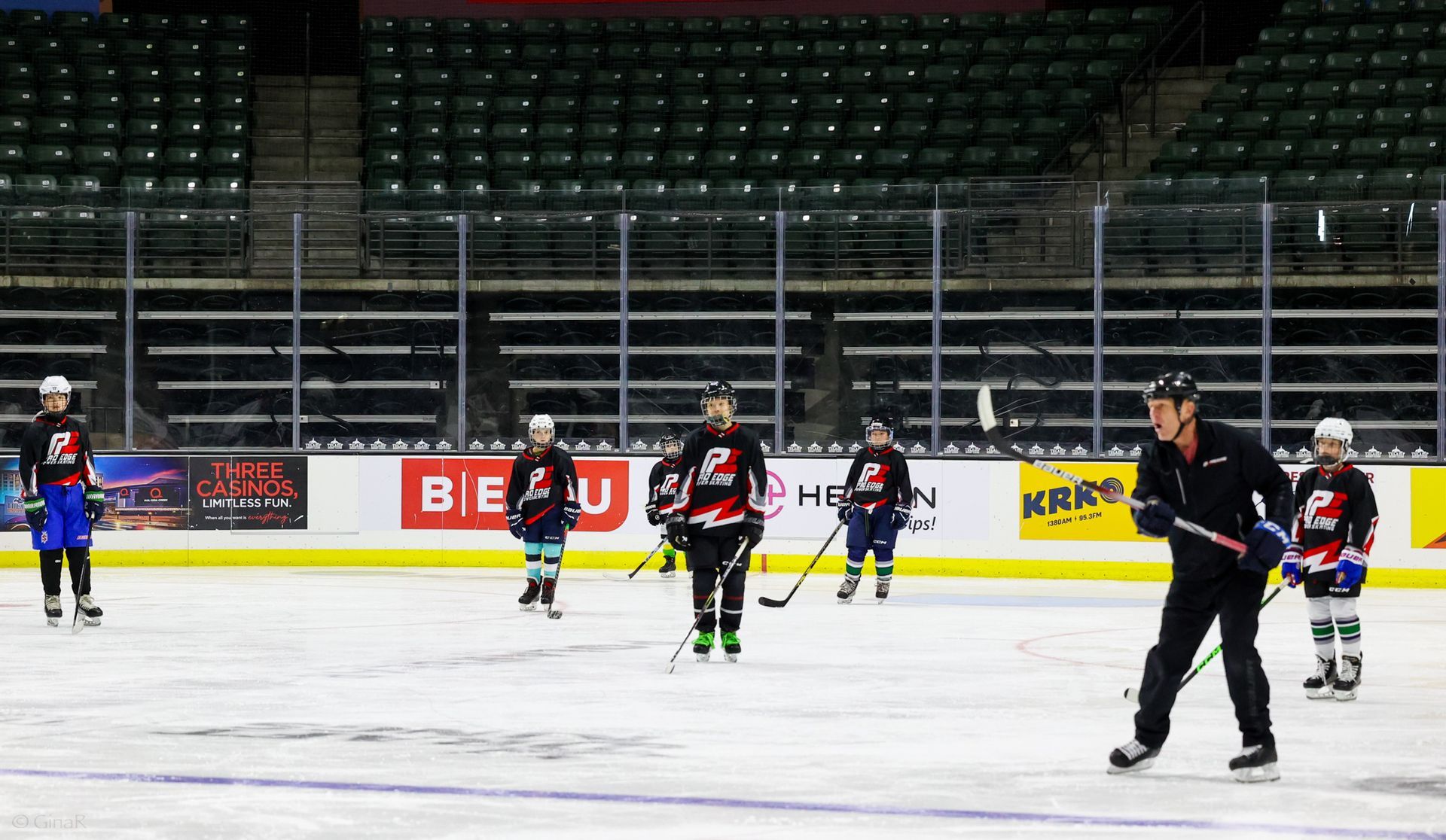 Ice hockey players on an indoor rink during practice, with one skater in the foreground.