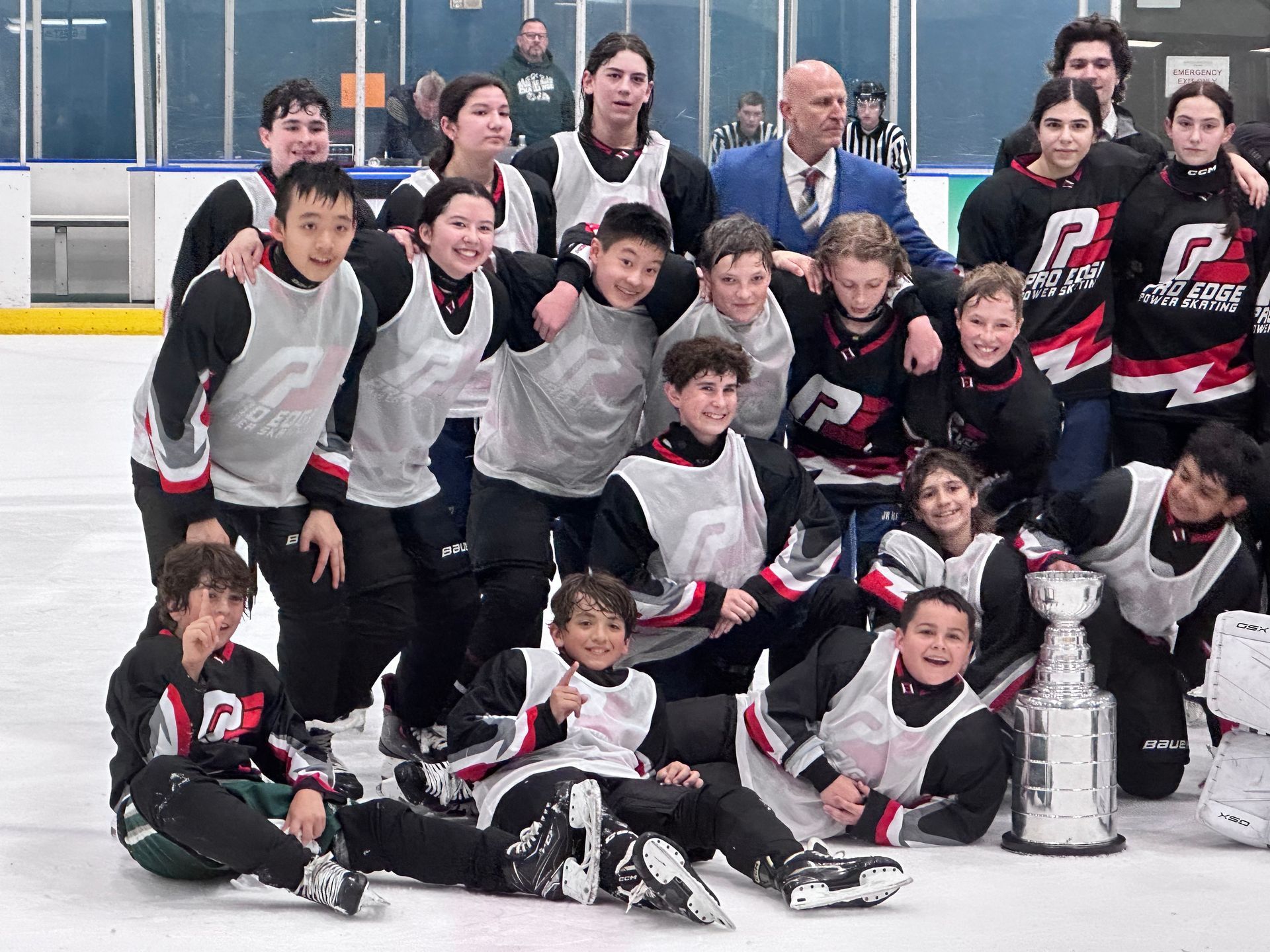 Youth hockey team posing on the ice with a large trophy and championship banner backdrop
