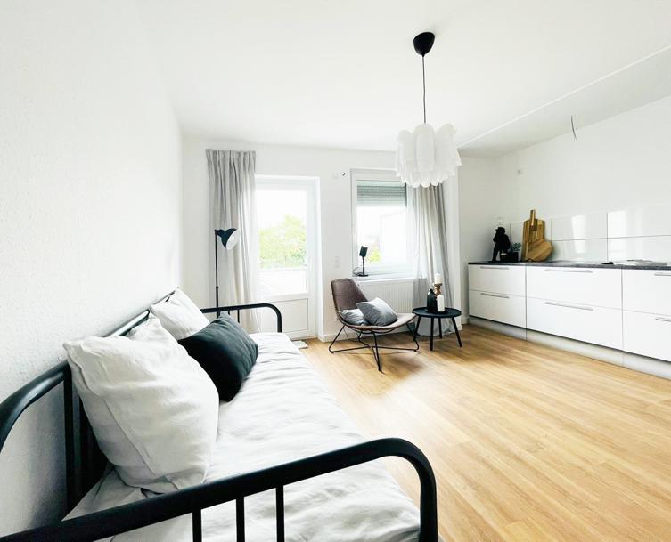 Ein Wohnzimmer mit Couch, Sessel, Tisch und Fenster.