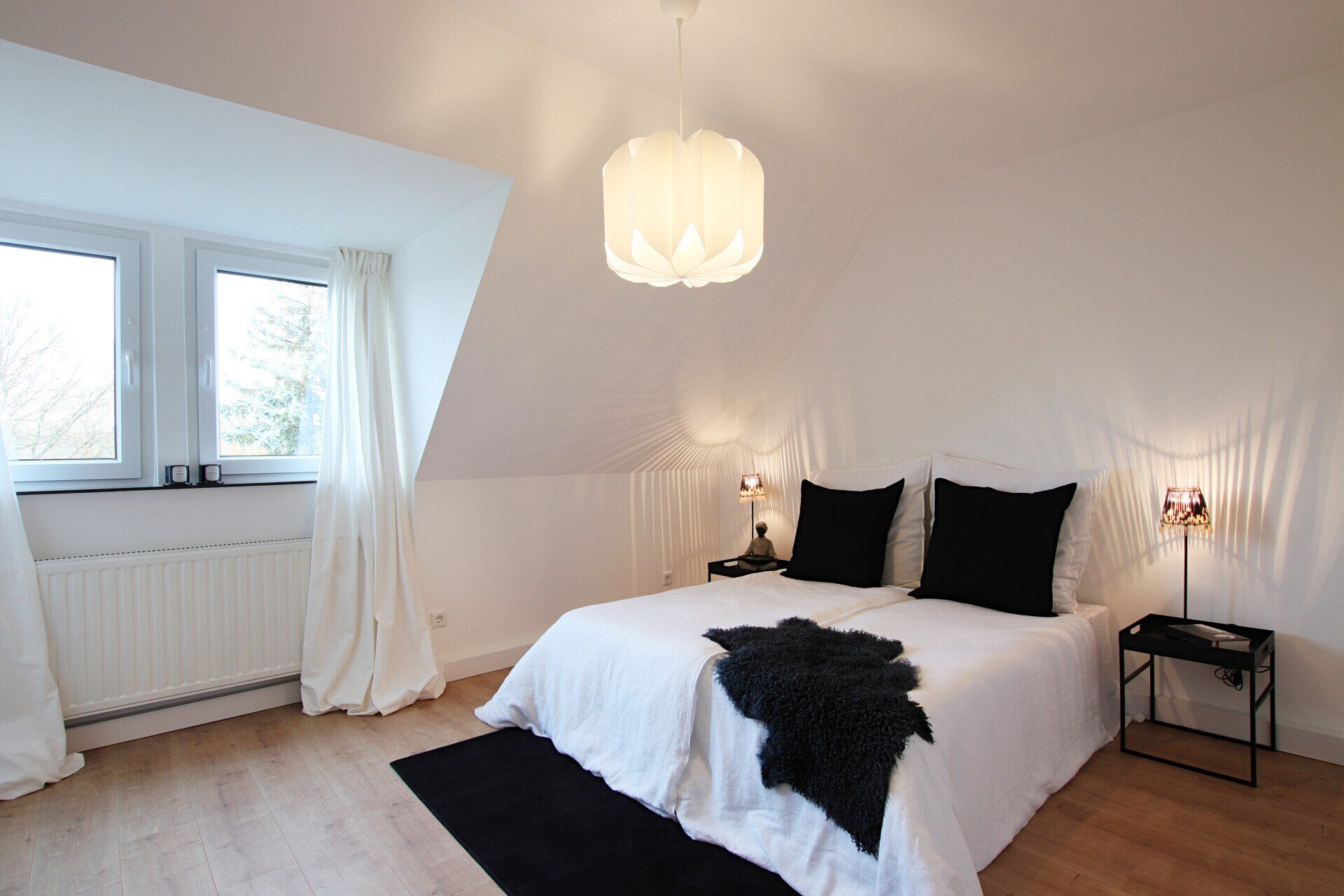 Ein Schlafzimmer mit einem weißen Bett und schwarzen Kissen
