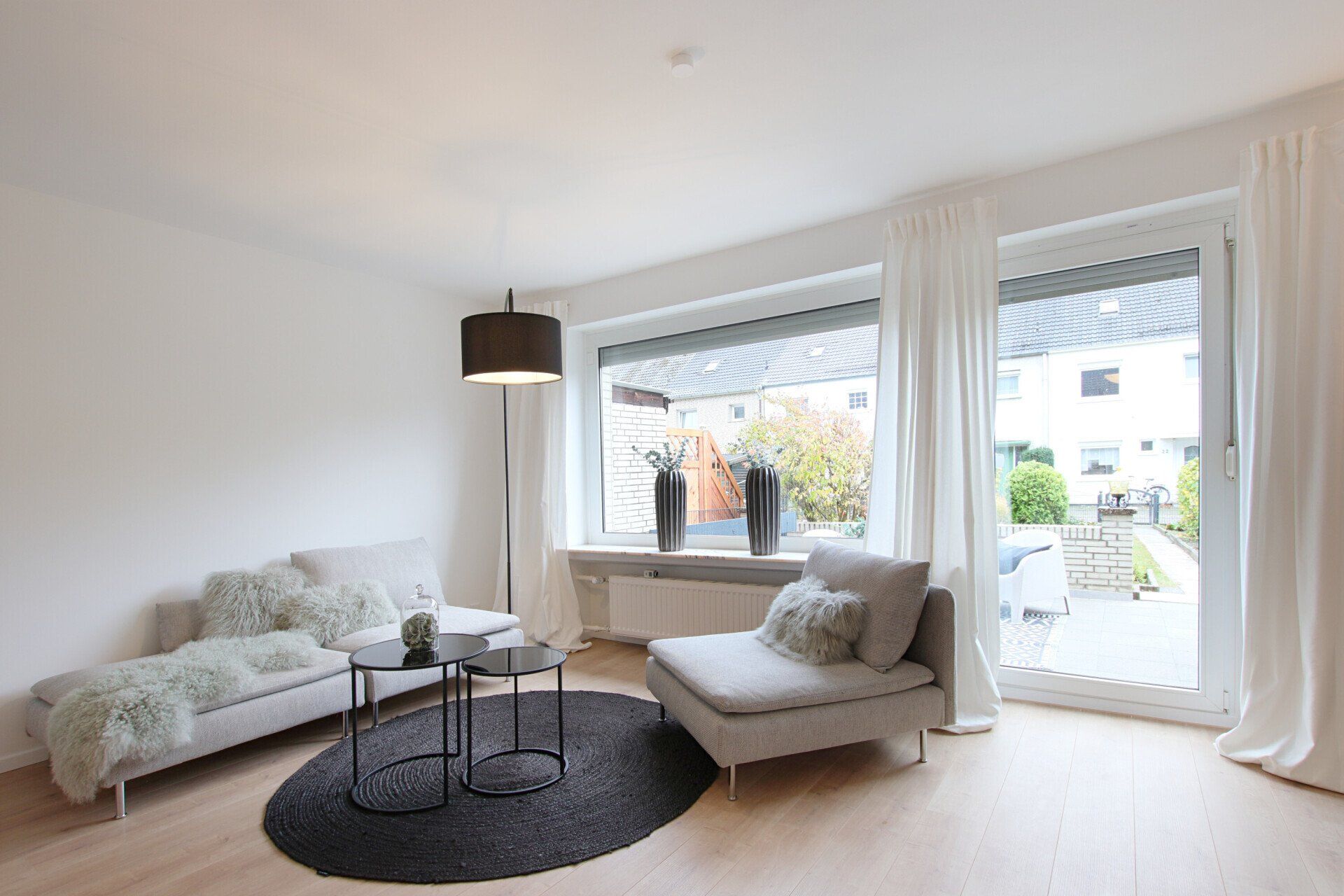 Ein Wohnzimmer mit Couch, Sessel, Tisch und Fenster.
