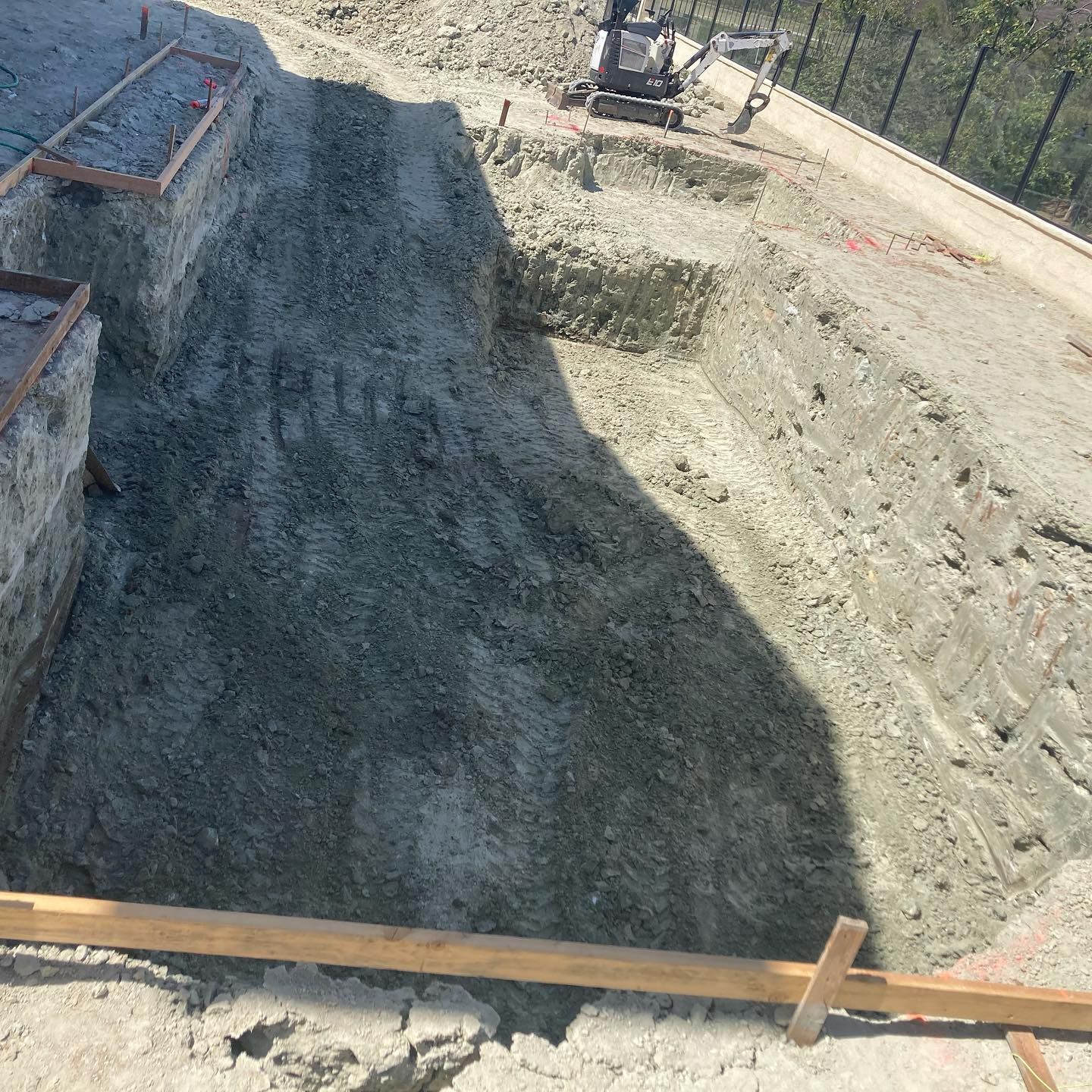 A construction site with a lot of dirt and a fence in the background.