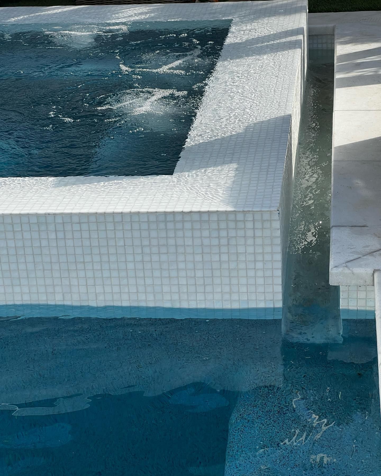 A swimming pool with blue water and white tiles