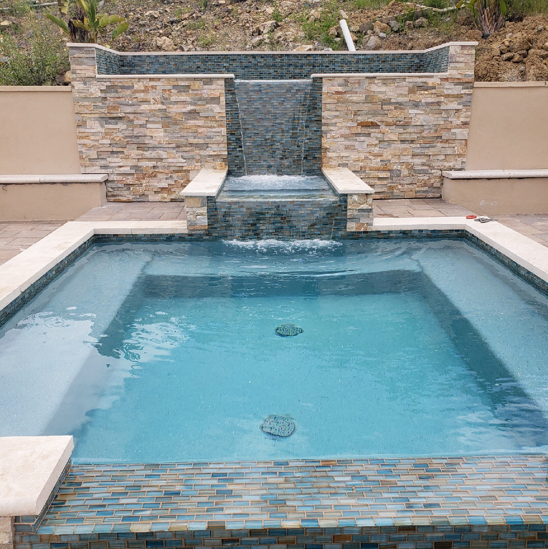 A large swimming pool with a waterfall in the background.