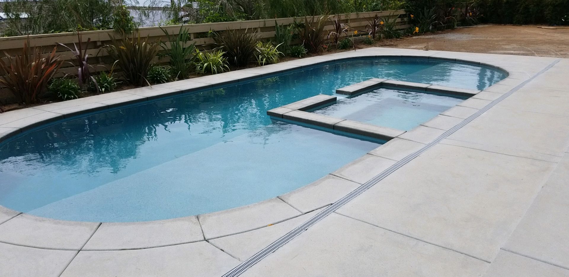 A large swimming pool with a hot tub in the middle of it.