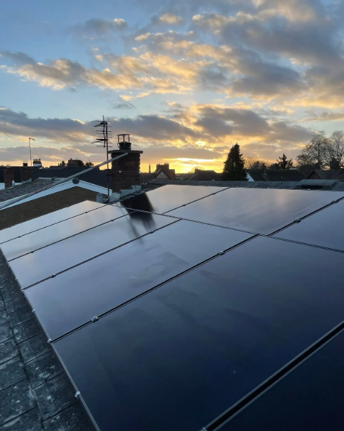 Solar panels on a rooftop with a sunset background.