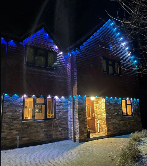 Two-story brick house illuminated with blue and white Christmas lights.