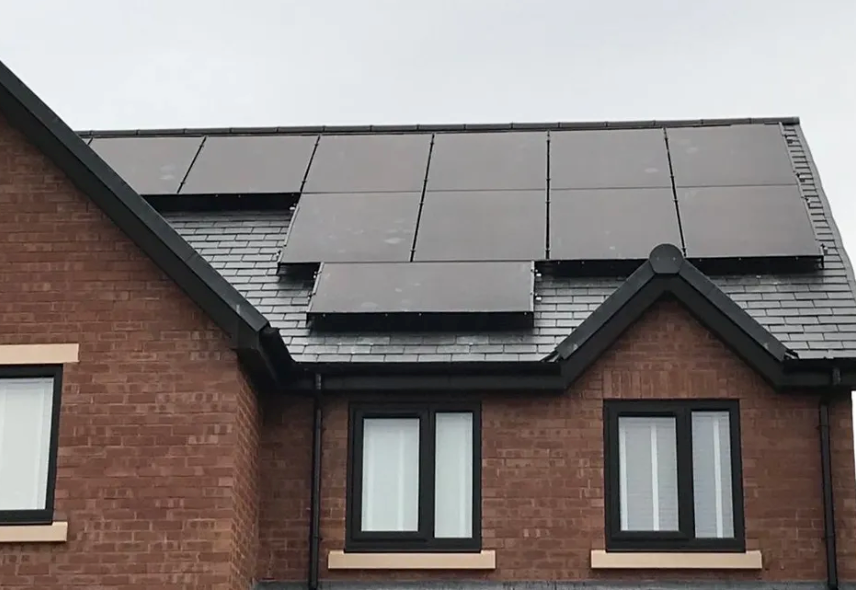 Brick house with solar panels on the roof. Dark gray roof and window frames.