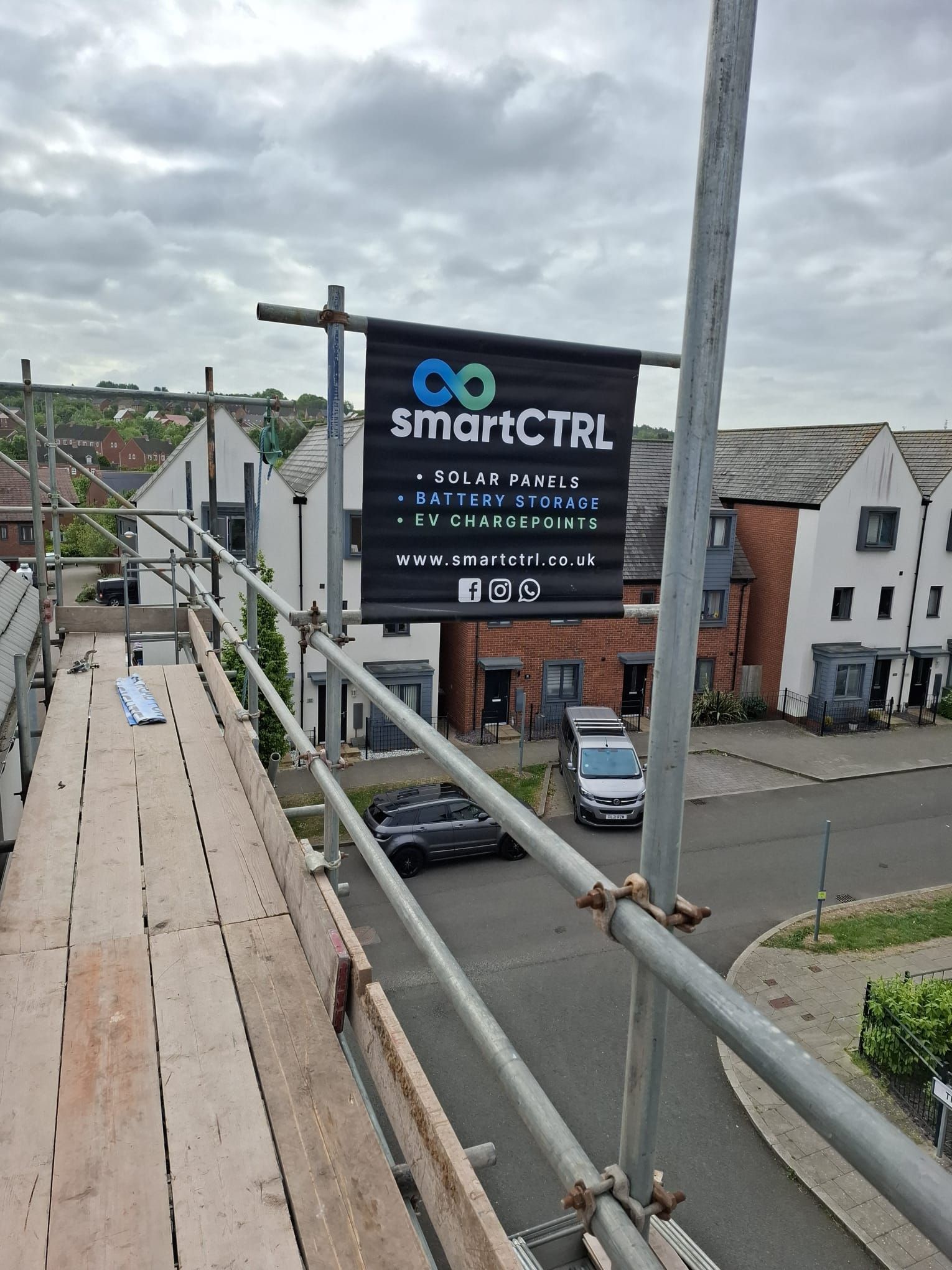 Sign for SmartCTRL displayed on scaffolding; houses and street in background.