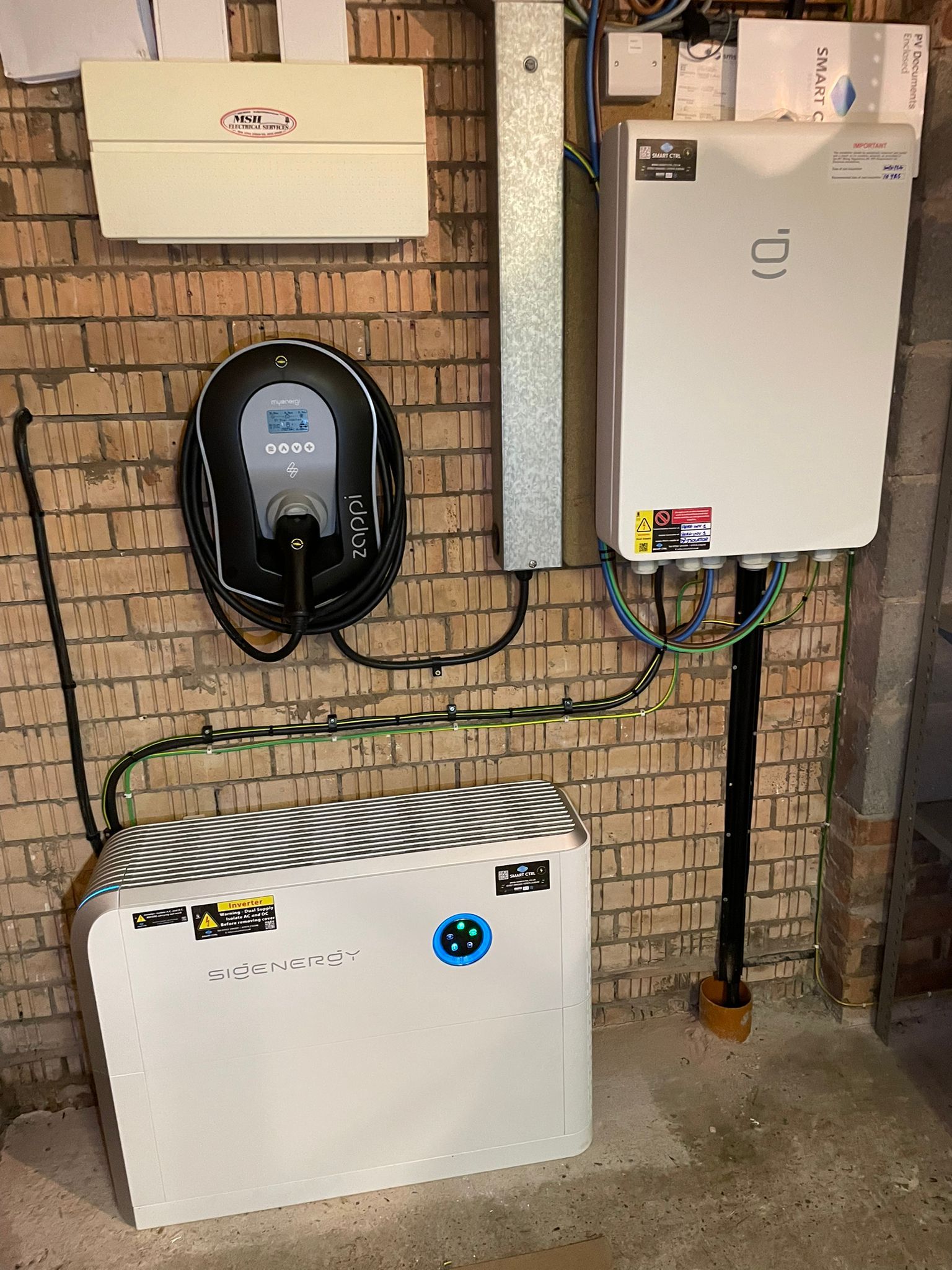 Electric vehicle charging station and solar power equipment mounted on a brick wall.