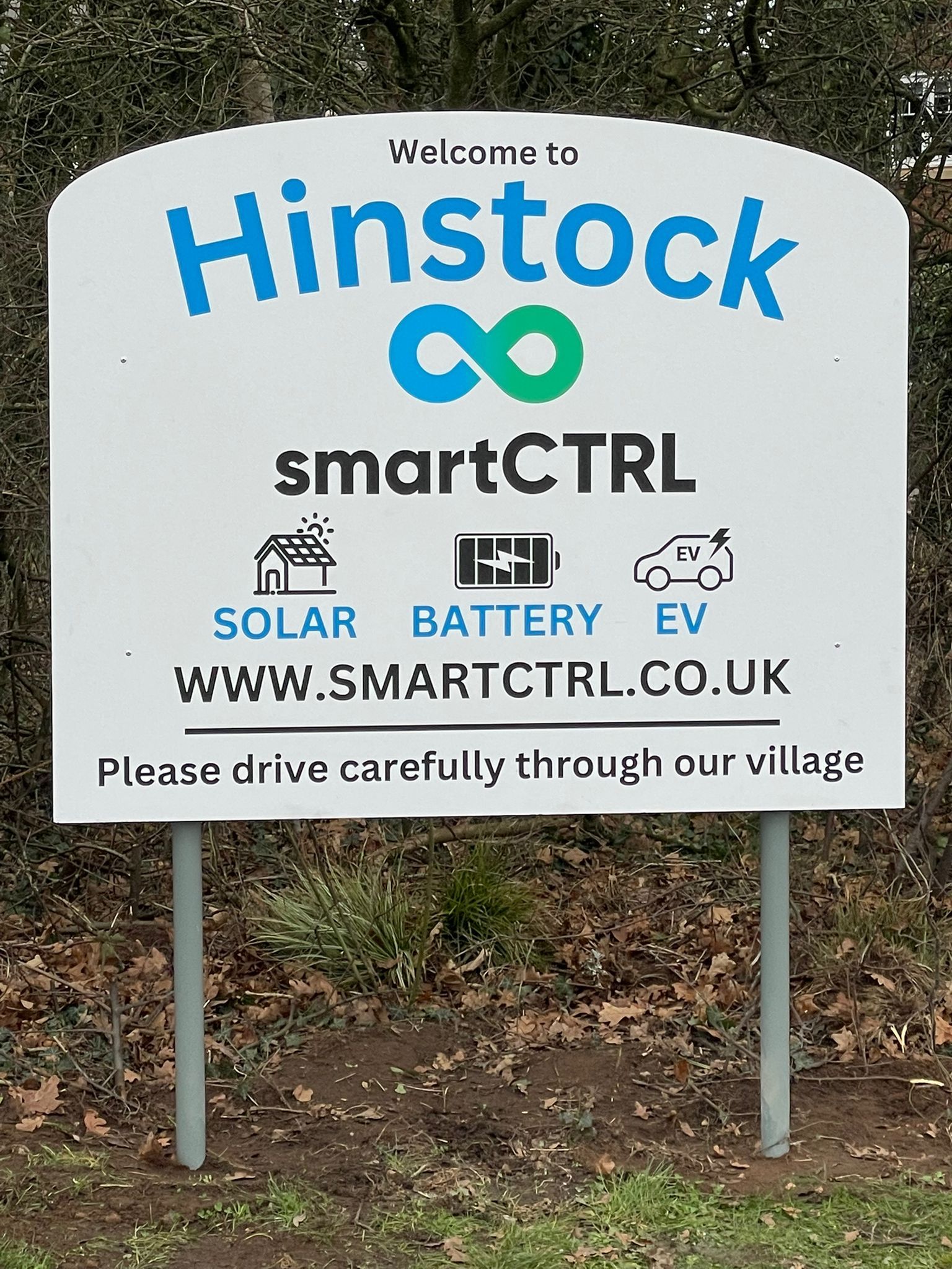 Sign welcoming visitors to Hinstock, promoting SmartCTRL with solar, battery, and EV imagery.