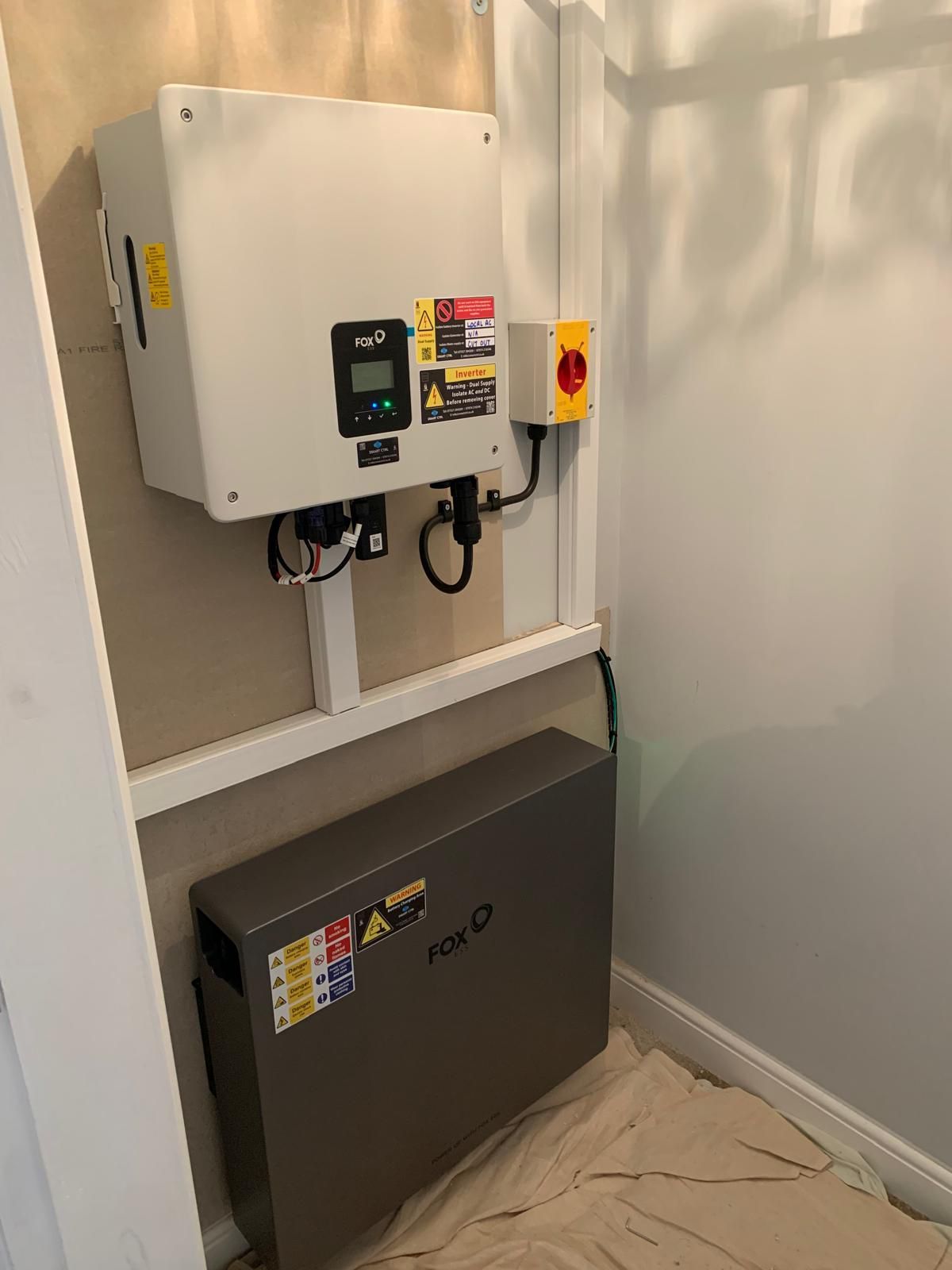 Solar power equipment, an inverter and battery, mounted on a wall in an indoor setting.