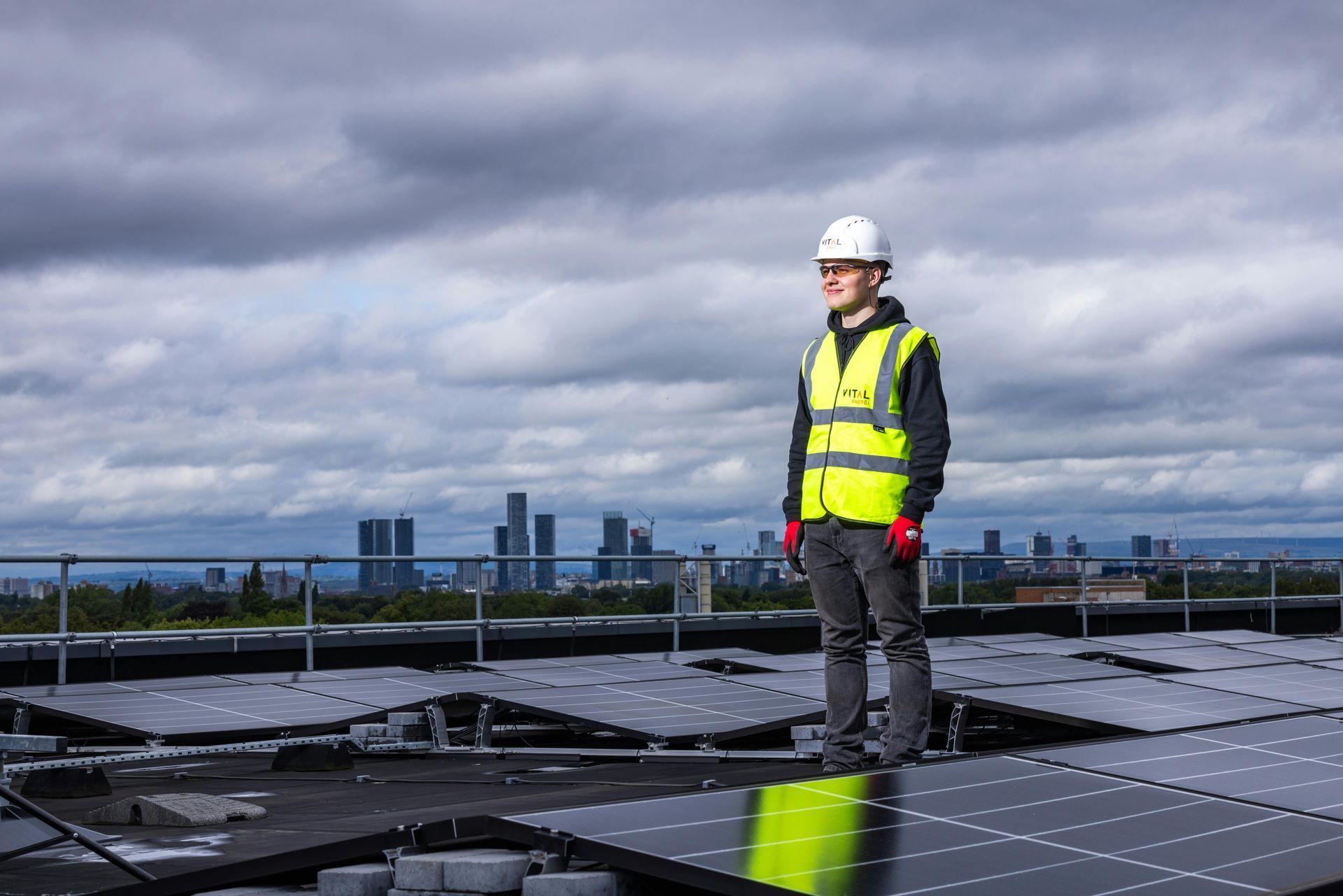 A man is standing on top of a roof with solar panels.