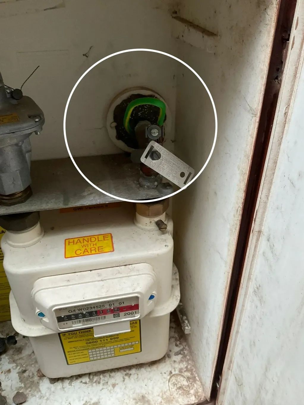 Gas meter inside a metal box; highlighted outlet with green and black wires and a disconnected tag.