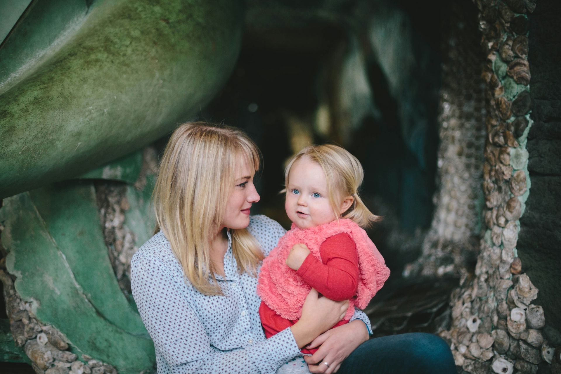 Woman holding smiling child in a rocky cave-like opening