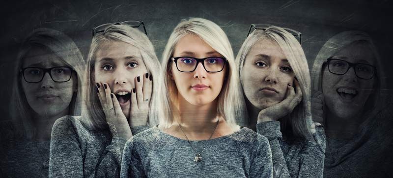 A woman wearing glasses has many different faces on her face, representing Emotional Release How Emotions Get Stuck in the Body