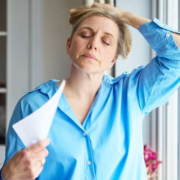 Woman with hormone imbalances waving a fan from hot flashes