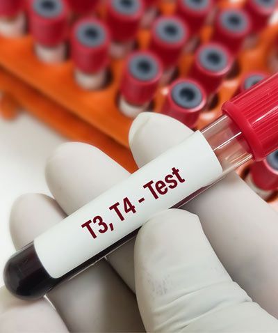 Gloved hands holding a blood sample vial labeled