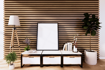 A living room with a wooden wall , a table , a lamp , and a picture frame.