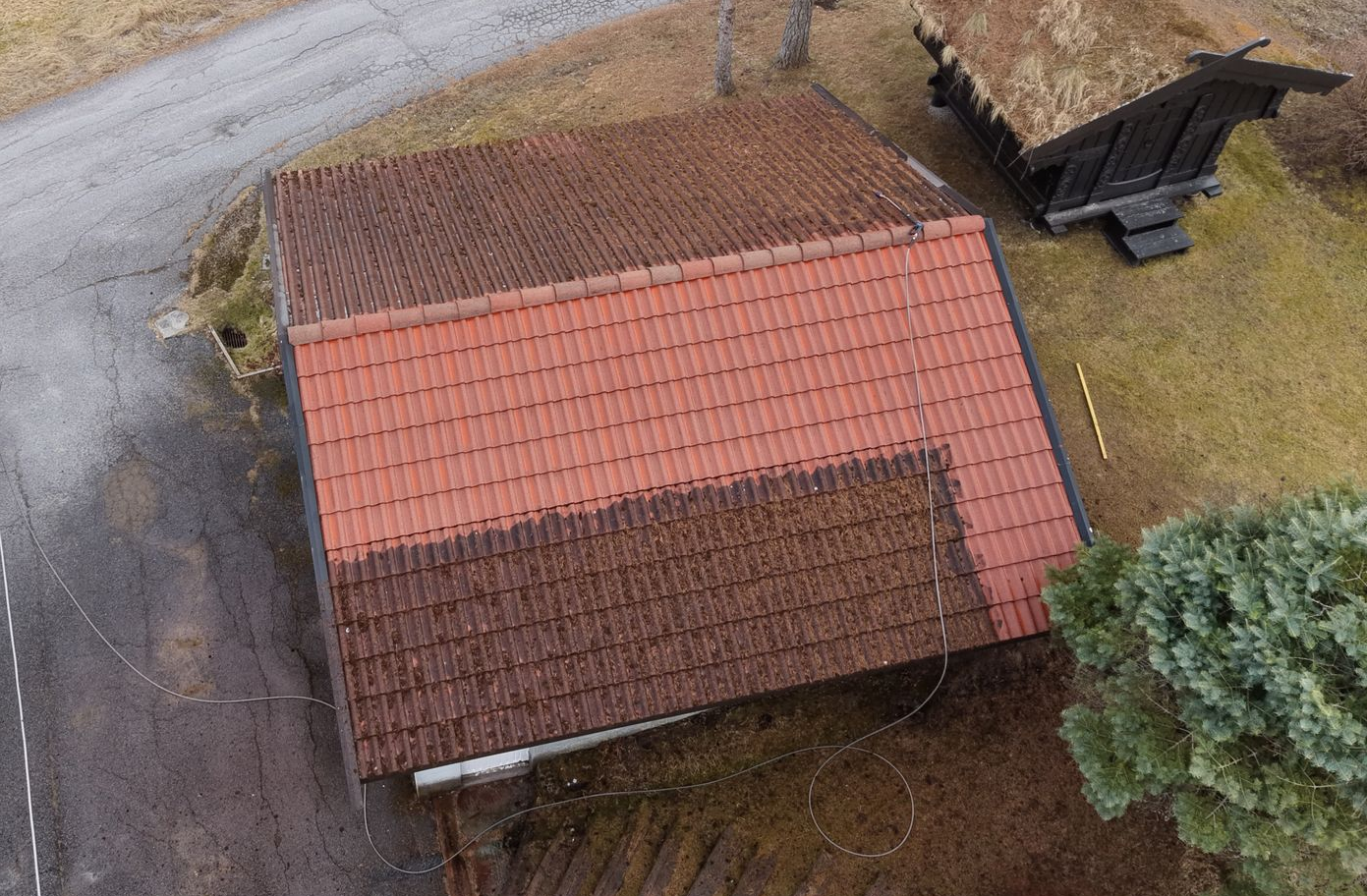 En luftfoto av en rektangulær bygning med et delvis rengjort rødt tegltak, som viser en kontrast mellom gammelt og nytt.