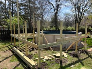 Partially built wooden above-ground pool frame in a grassy yard Partially built wooden above-ground pool frame in a grassy yard