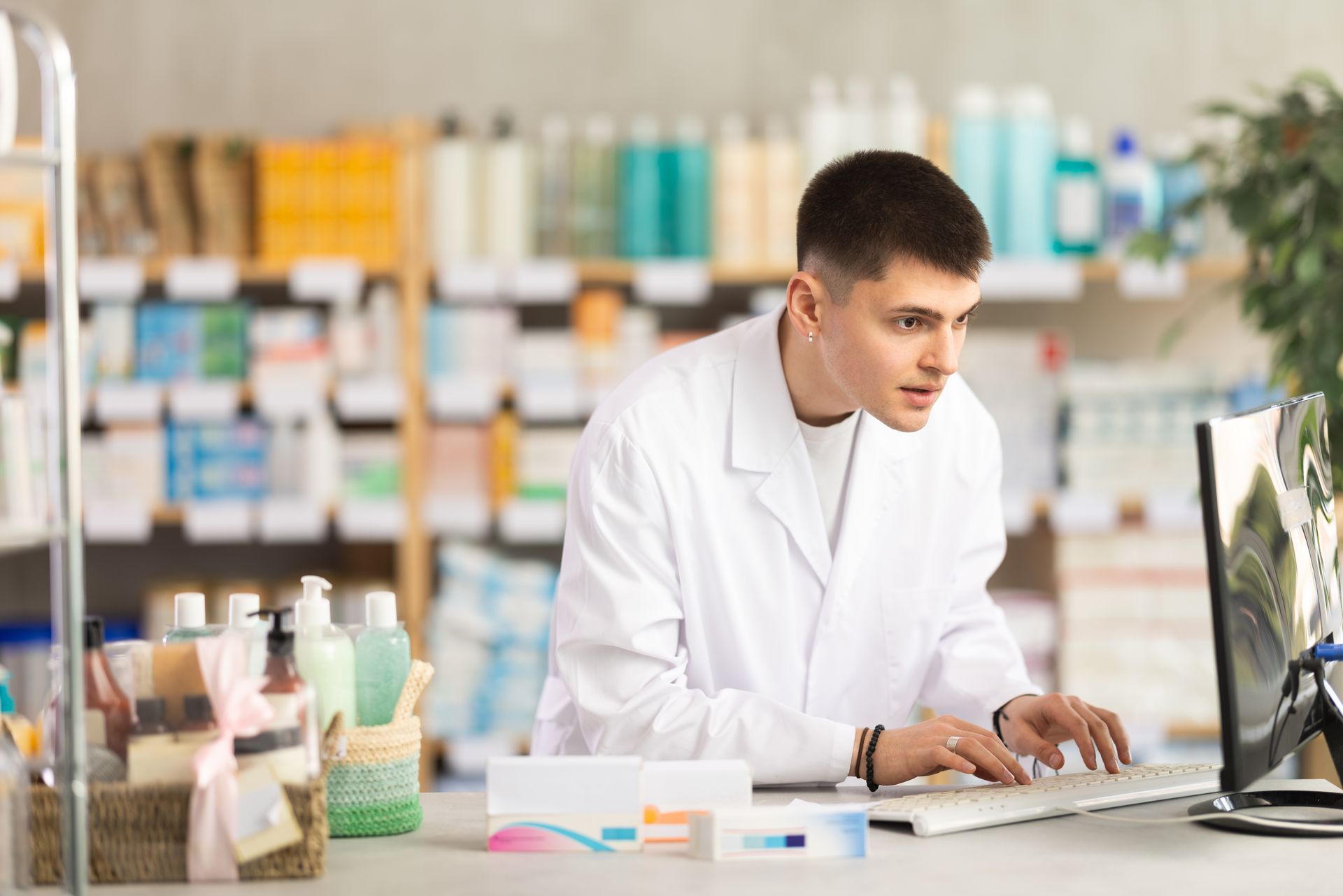 Scientist in a white lab coat working at a laptop in a bright laboratory setting