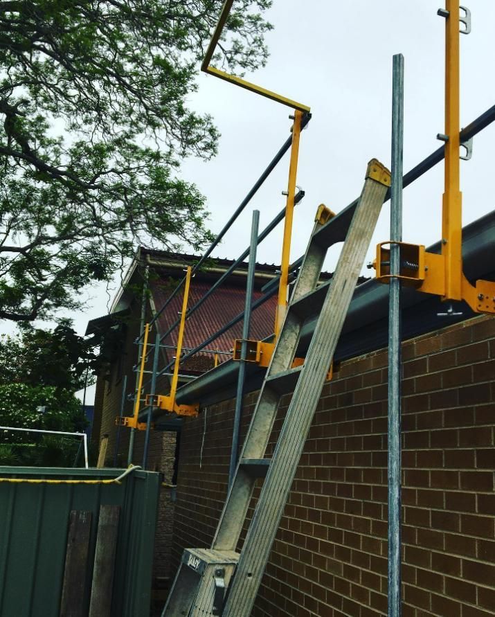 A Ladder Is Attached to A Yellow Railing on The Side of A Building — Site Safety NSW in Sandgate, NSW