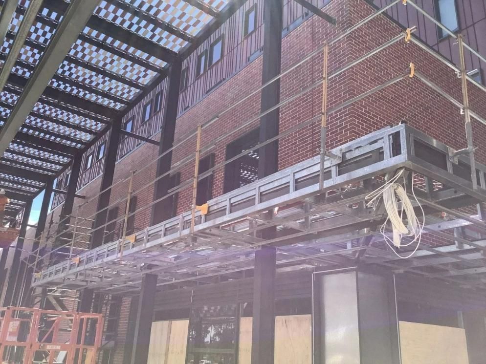 A Large Brick Building Under Construction with Scaffolding on The Side of It — Site Safety NSW in Sandgate, NSW