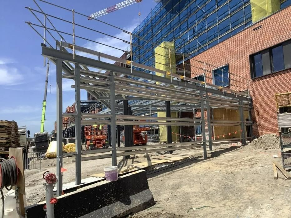 A Metal Structure Is Being Built in Front of A Brick Building — Site Safety NSW in Sandgate, NSW