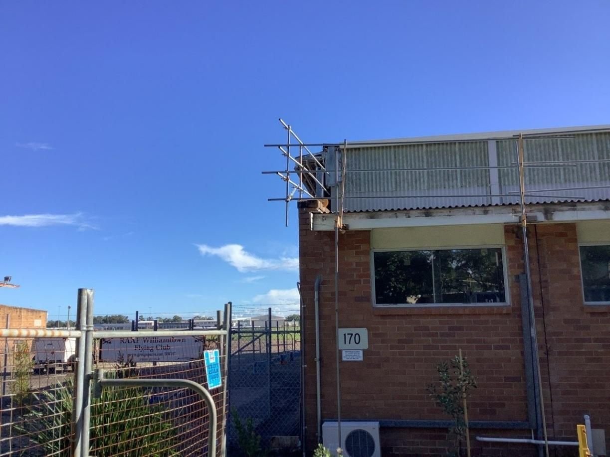 A Brick Building with Scaffolding on The Side of It — Site Safety NSW in Sandgate, NSW