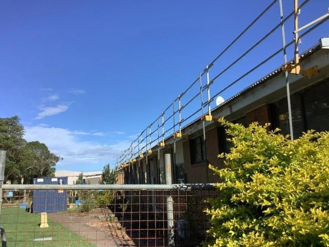 A House with Scaffolding on The Side of It and A Fence in Front of It — Site Safety NSW in Sandgate, NSW