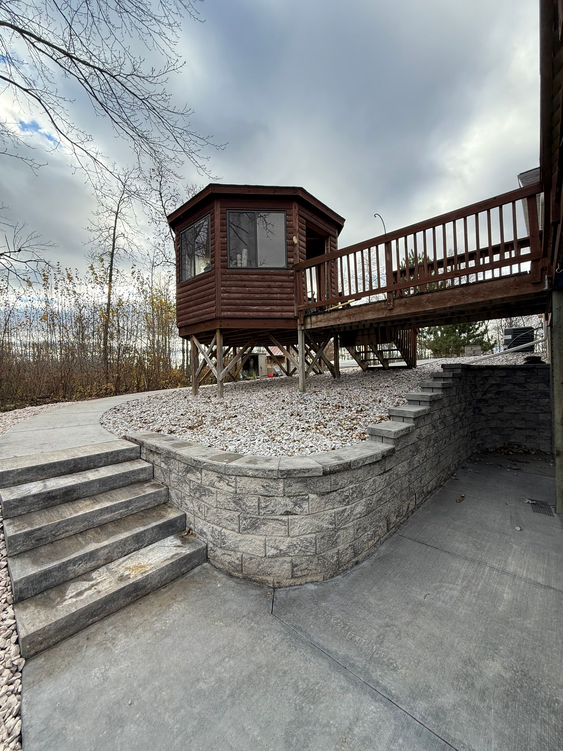 Wooden lookout platform with stairs and railing on a stone slope under a cloudy sky