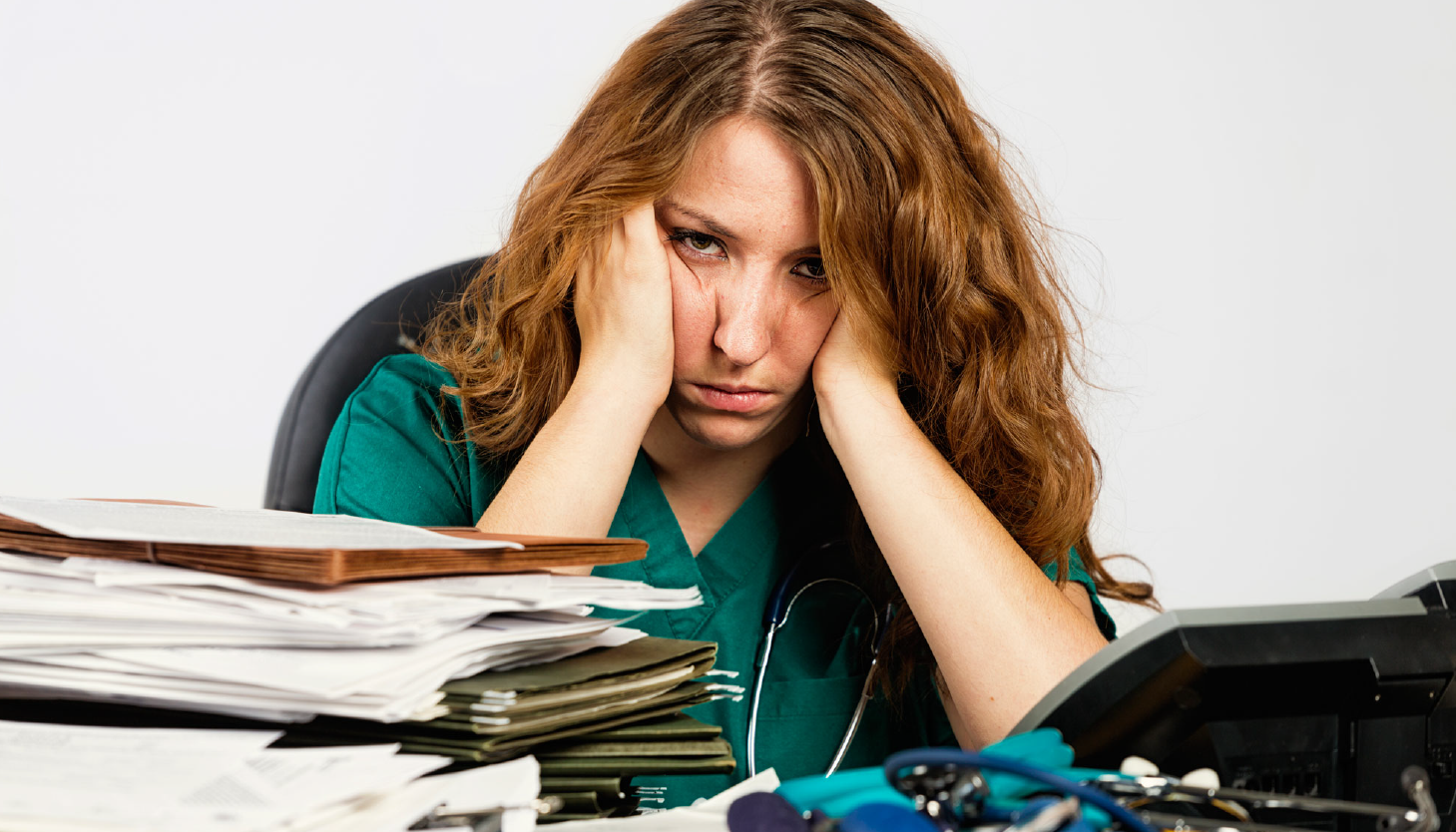 A nurse wearing a headset is sitting in front of a computer.