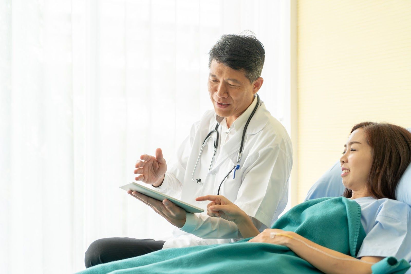 A doctor is talking to a patient in a hospital bed.