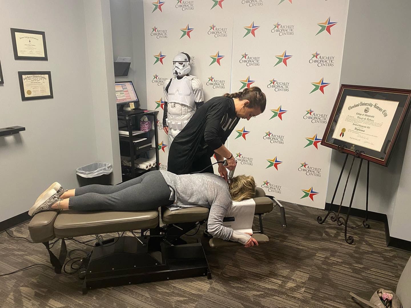 Person receiving a back adjustment on a treatment table in a clinic room
