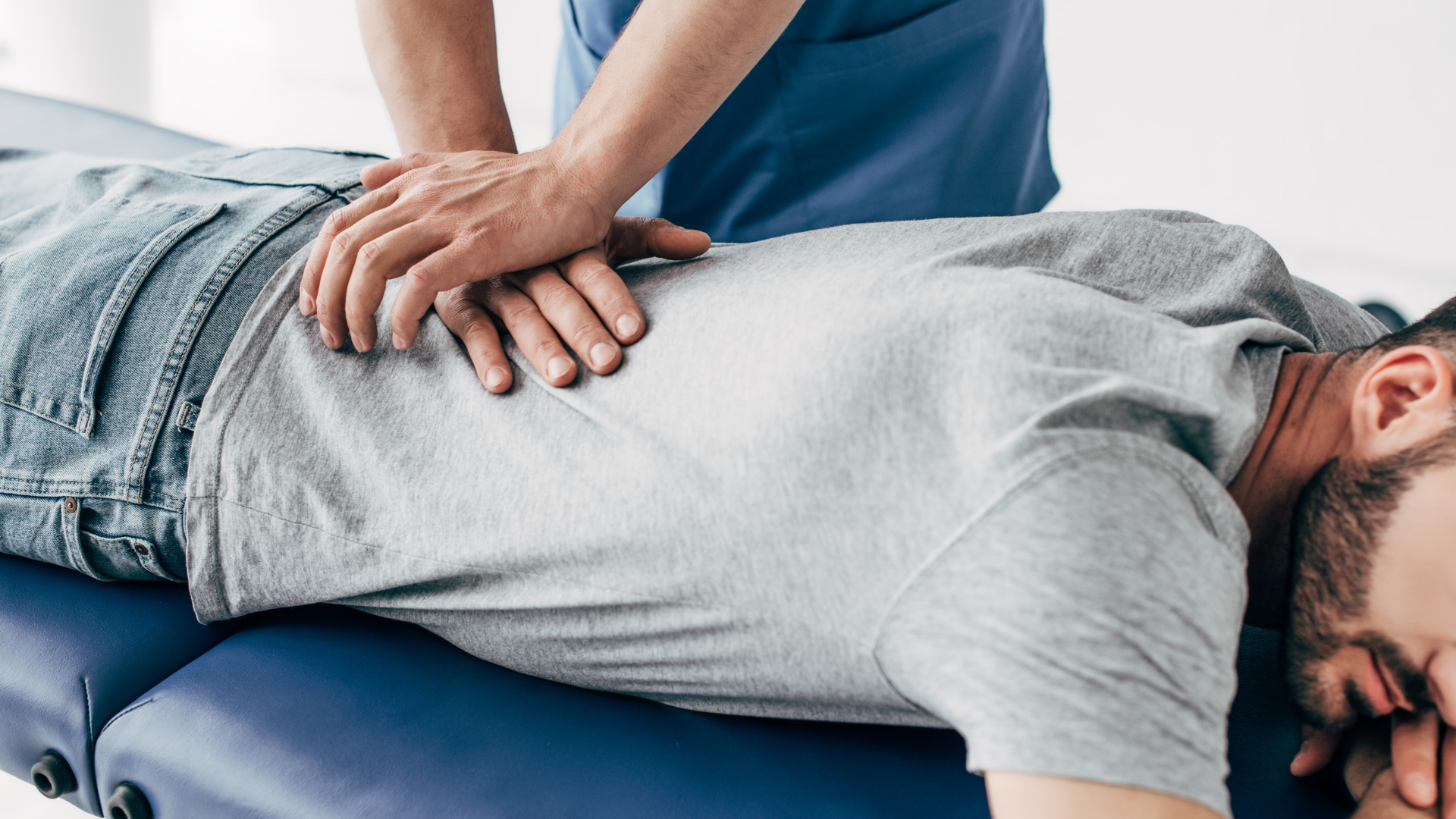 Healthcare worker examining a seated patient’s back in a clinic room
