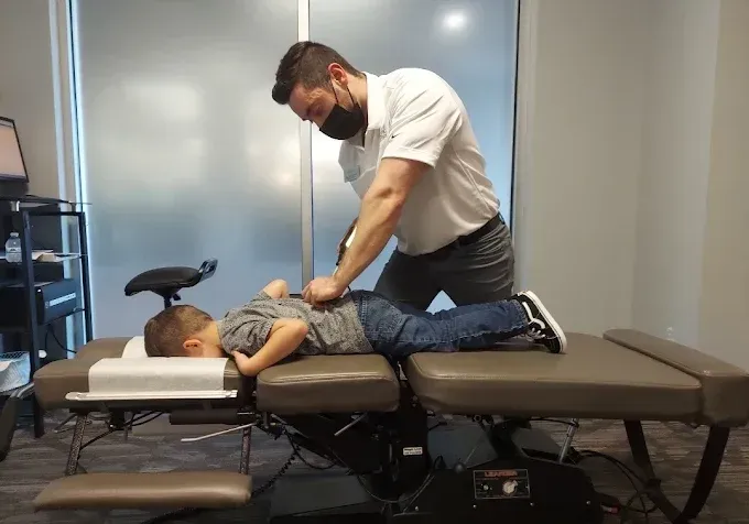 Chiropractor adjusting a patient on a treatment table in a clinical office