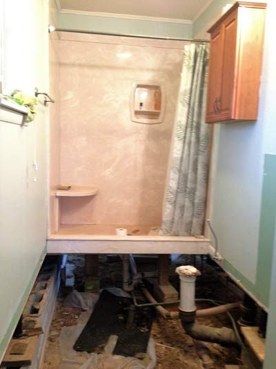 Bathroom under renovation, shower stall, missing floor, wall cabinets.