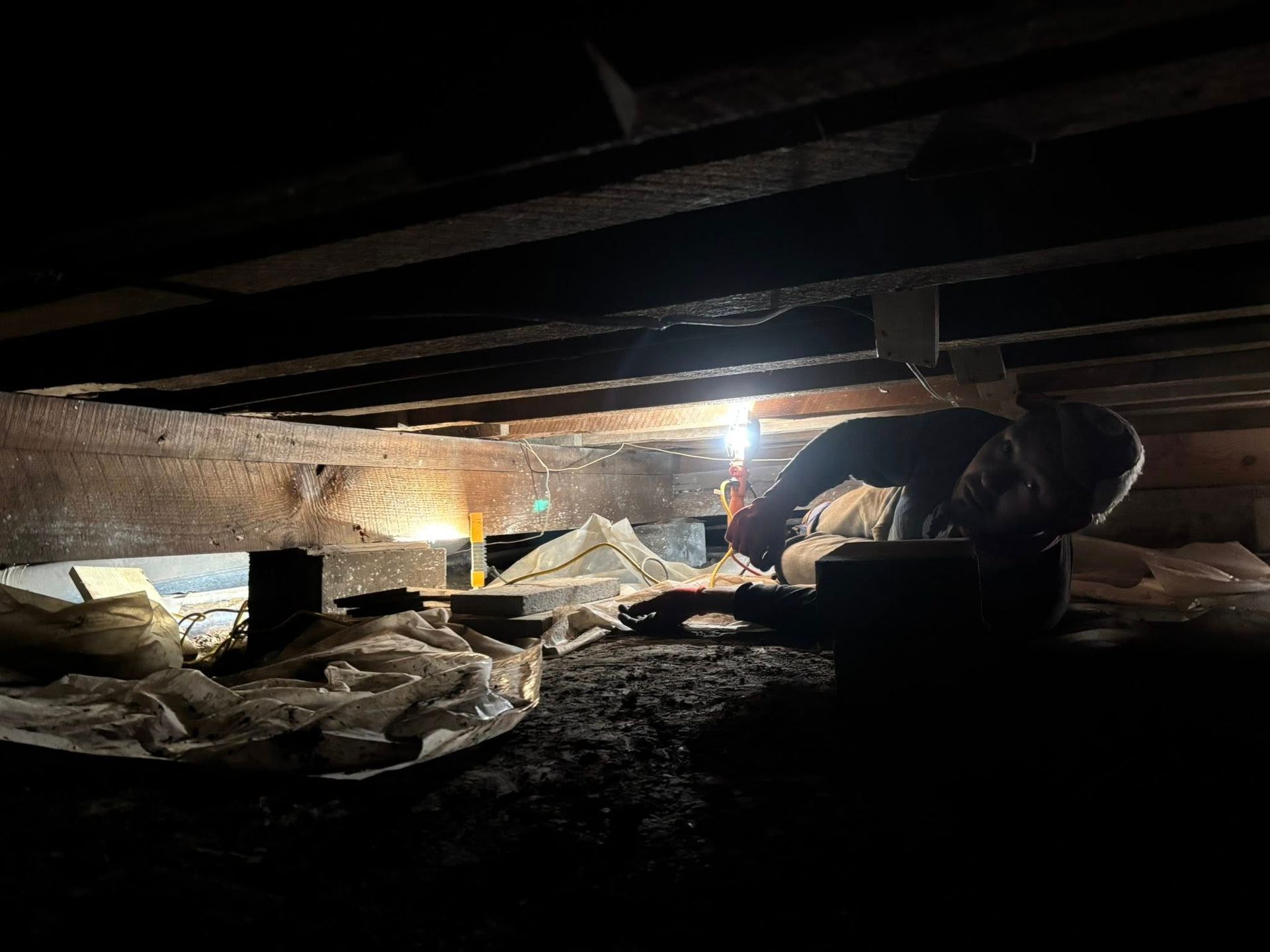 An inspector examining a sinking foundation in a crawl space under a home.