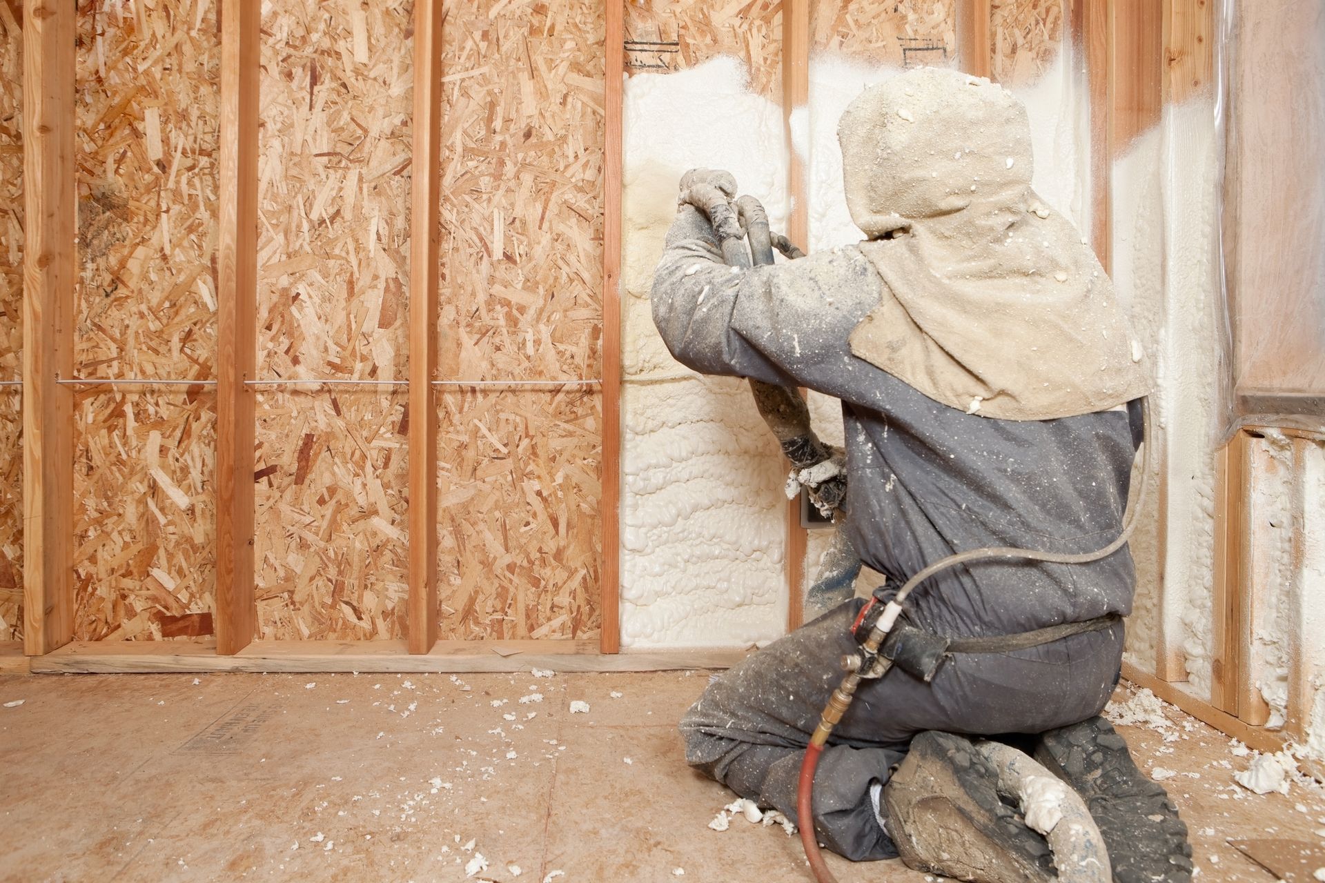 A person measures an old brick foundation in a dirt crawlspace with a tape measure.