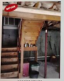 Basement stairs with wooden support beams and a partial view of a room.