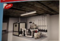 An industrial space with mechanical equipment, pipes, and a fluorescent light.