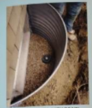 Metal well is installed with a foundation wall in an outdoor setting.