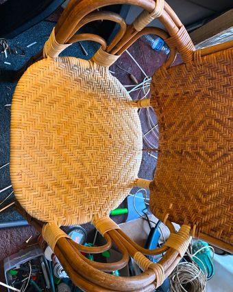 A wicker chair is sitting on top of a pile of wicker items.