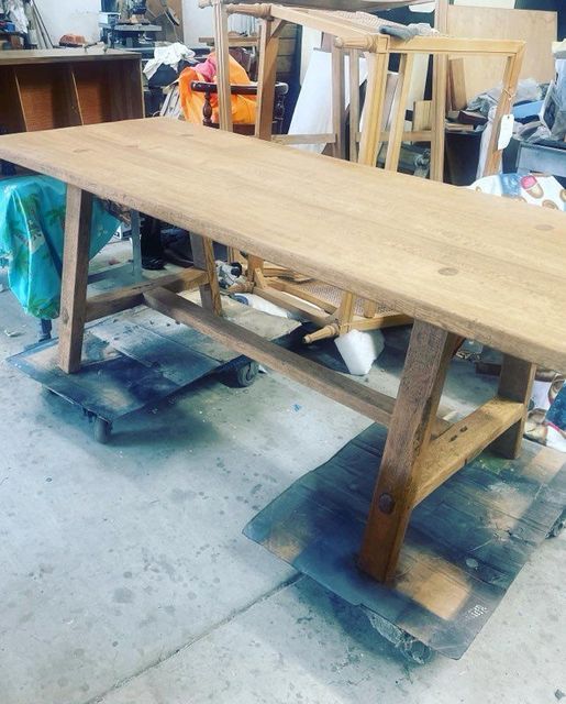 A wooden table is sitting on a concrete floor in a workshop.