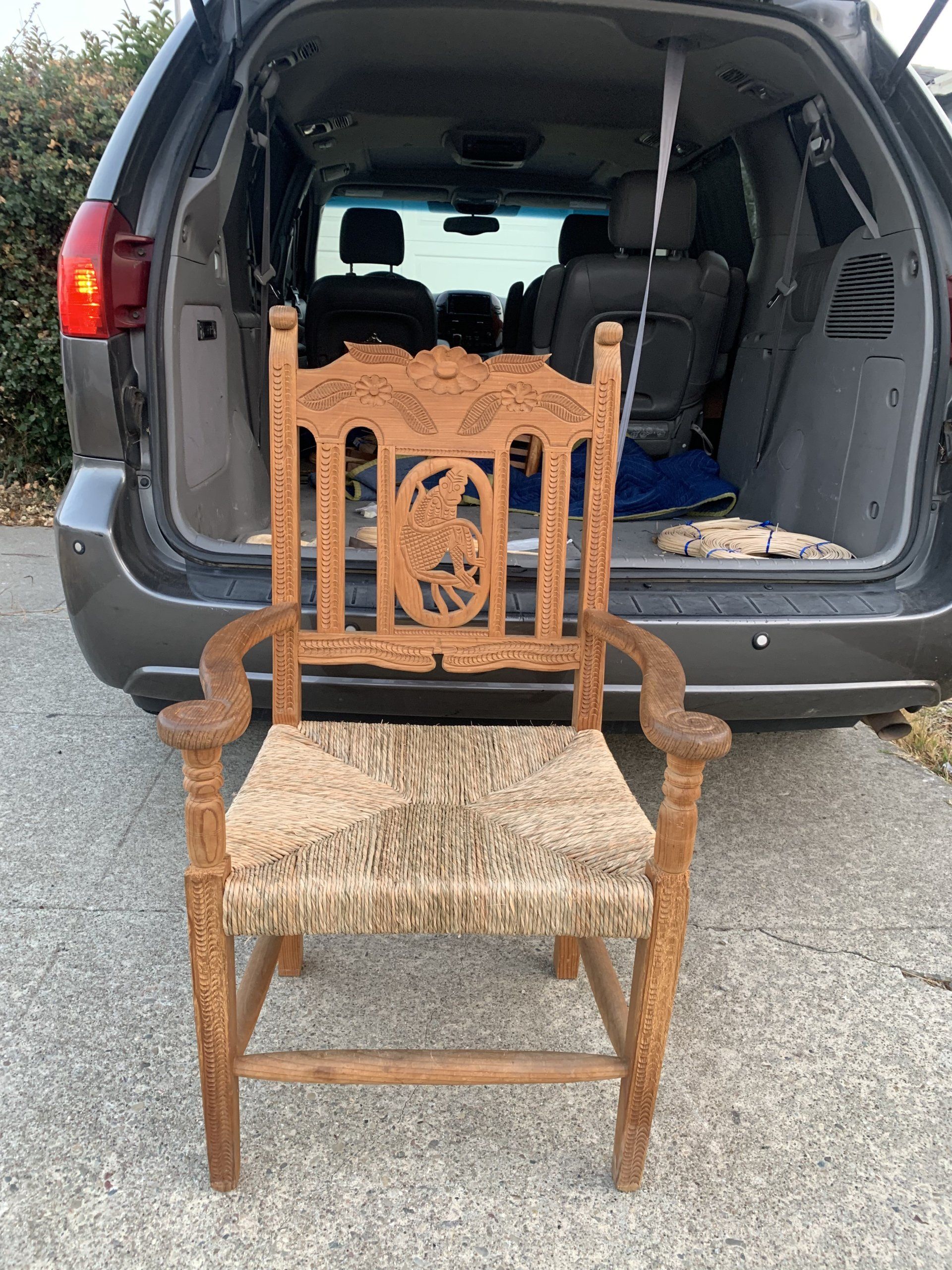 A wooden chair is sitting in the back of a minivan.