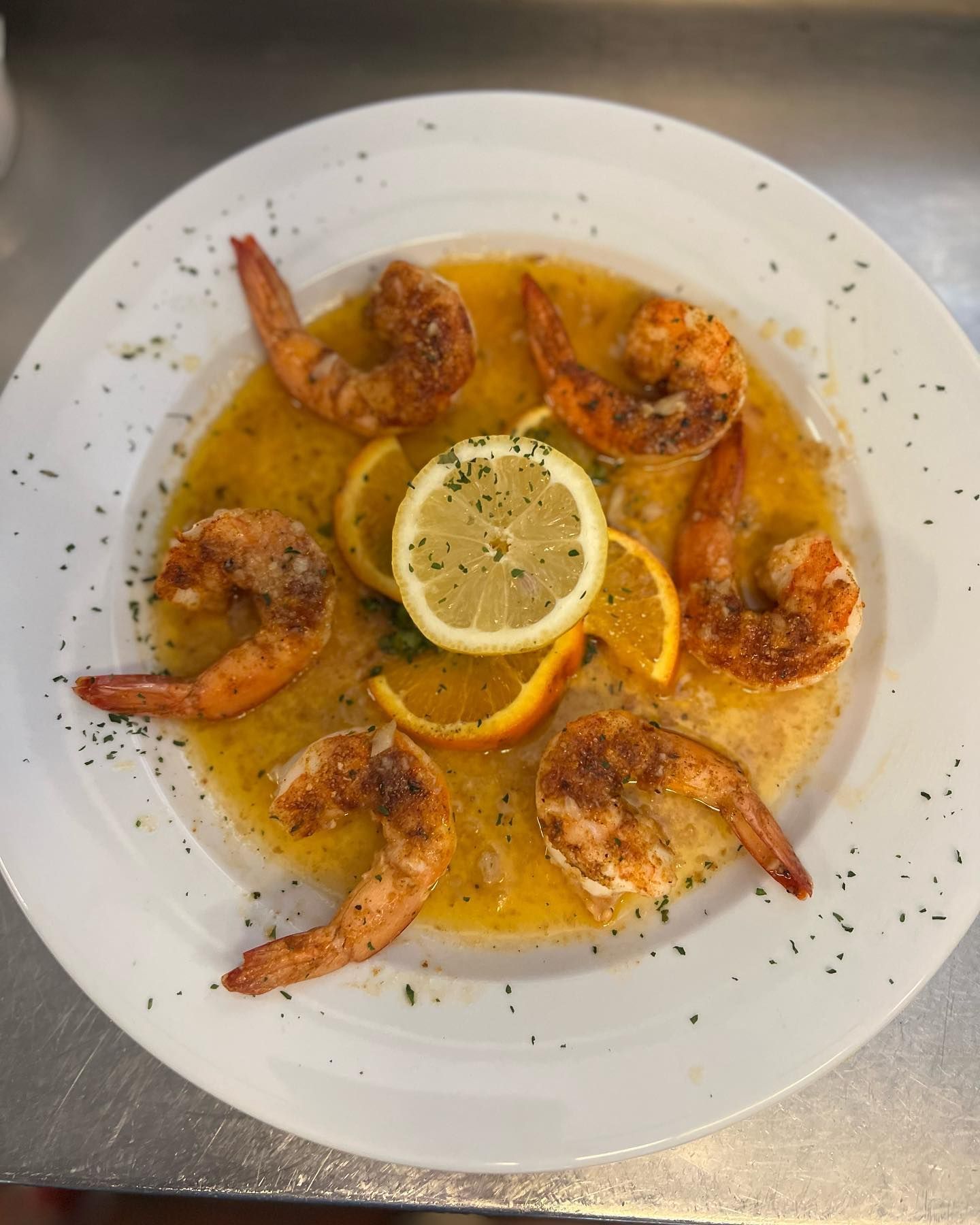 A white plate topped with shrimp and a lemon slice.