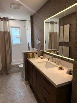 Modern bathroom with double vanity, large mirror, glass shower, and gray tile floor