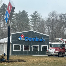 Domino’s storefront with a red truck parked outside in a snowy winter setting