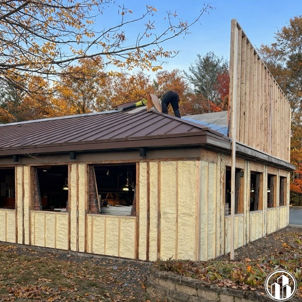 Partially built house with insulated walls and workers on the roof in an autumn yard